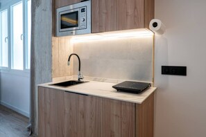 Eine kleine Küche mit eingebauter Mikrowelle, einem Spülbecken und einer Arbeitsplatte mit einem Toaster.