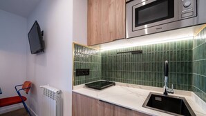 A compact kitchen with a microwave, a sink, and a stove. - Sol Atelier | Apartments by Monaro* * * * * (Madrid)