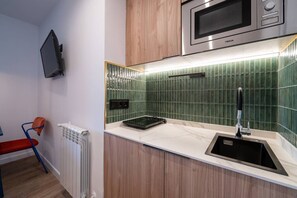 A compact kitchen with a microwave, a sink, and a stove. - Sol Atelier | Apartments by Monaro* * * * * (Madrid)
