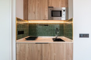 Une cuisine compacte équipée d’un four à micro-ondes encastré, d’un évier et d’une plaque de cuisson.