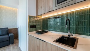A modern kitchen with a built-in microwave, a stainless steel sink, and a green tiled backsplash. - Sol Atelier | Apartments by Monaro* * * * * (Madrid)