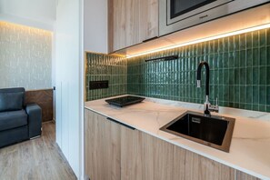 A modern kitchen with a built-in microwave, a stainless steel sink, and a green tiled backsplash. - Sol Atelier | Apartments by Monaro* * * * * (Madrid)
