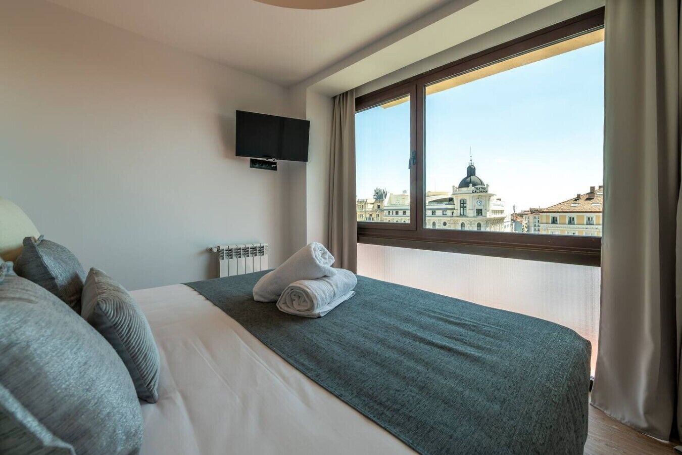 Une chambre d’hôtel équipée d’un lit, d’un téléviseur à écran plat, d’une fenêtre donnant sur la ville et d’un radiateur.