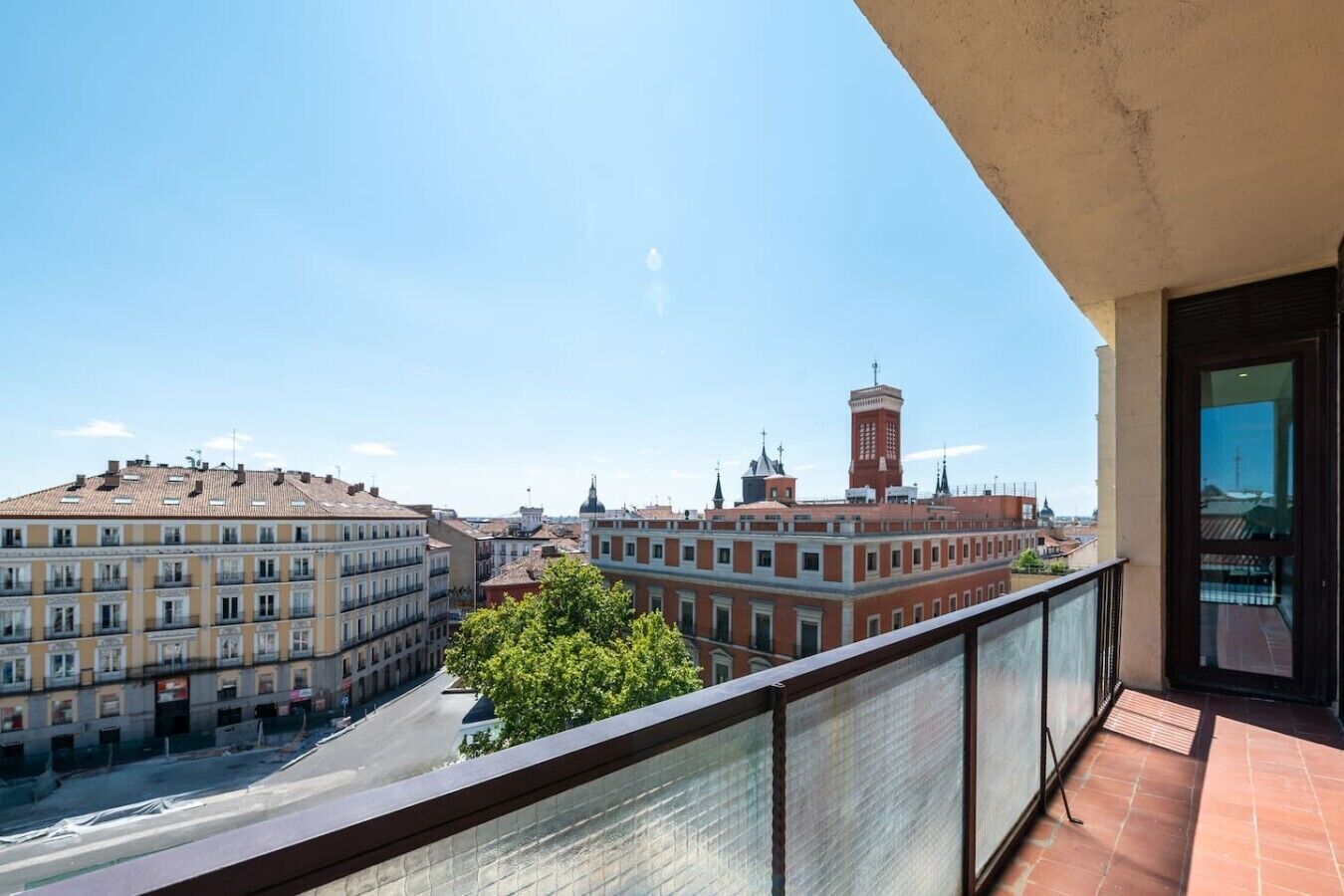 A balcony with a view of city buildings, including a prominent tower.