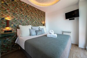 Une chambre à coucher avec un lit, des oreillers, un téléviseur fixé au mur et un radiateur.