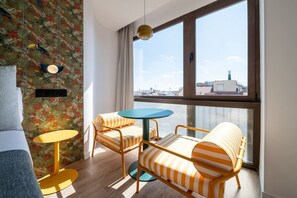 A modern room with a large window, a round table, two striped sofas, and a yellow lamp. - Sol Atelier | Apartments by Monaro* * * * * (Madrid)
