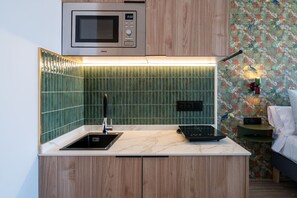 A compact kitchenette with a microwave, sink, and a small electric stove. - Sol Atelier | Apartments by Monaro* * * * * (Madrid)