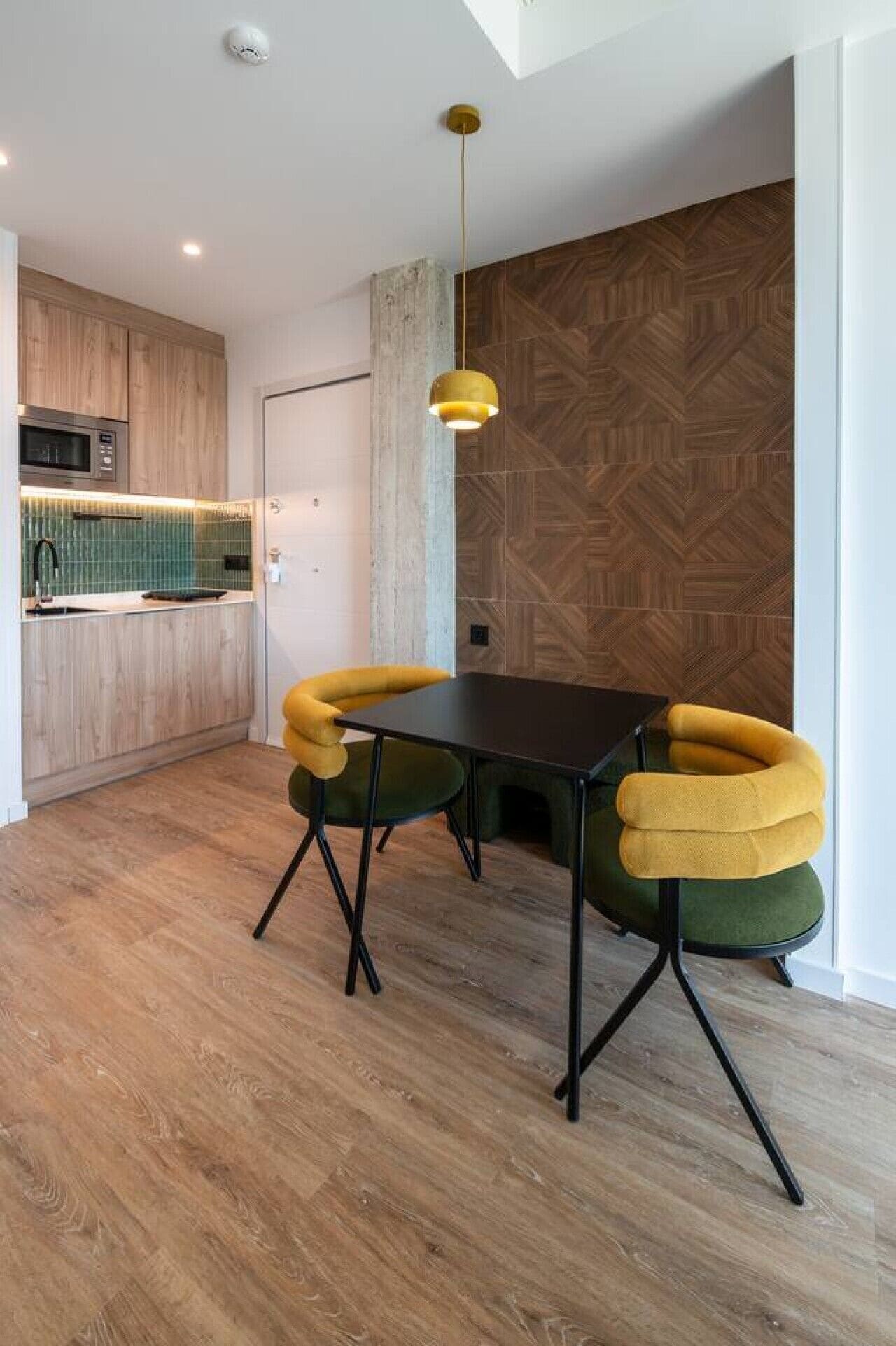 Eine moderne Küche mit Holzausstattung, einer Mikrowelle und einer grünen Spritzschutzwand.