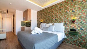 A modern bedroom with a large bed, a built-in kitchen, and a patterned wallpaper. - Sol Atelier | Apartments by Monaro* * * * * (Madrid)