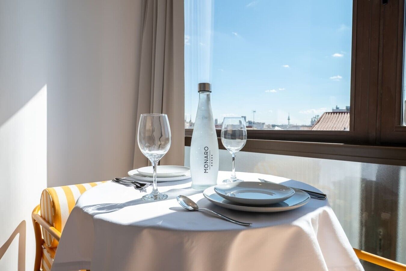 A table set for two with a bottle of water, two glasses, and cutlery.
