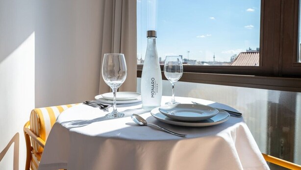 A table set for two with a bottle of water, two glasses, and cutlery. - Sol Atelier | Apartments by Monaro* * * * * (Madrid)
