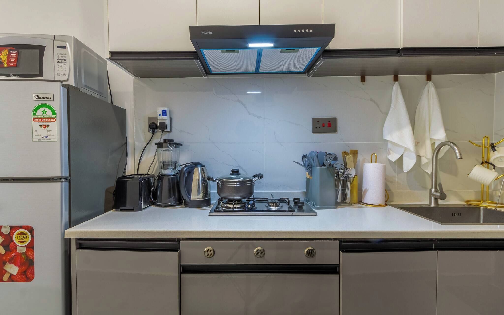 A modern kitchen with a microwave, toaster, kettle, and gas stove.