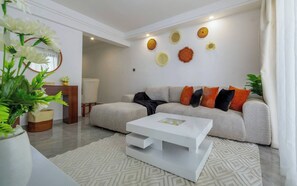 Una sala moderna con un sofá gris, una mesa de centro blanca y decoración en la pared.
