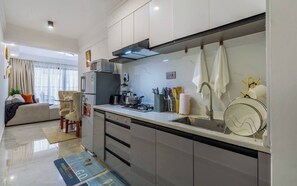 A modern kitchen with a gas stove, microwave, and a sink with a towel rack. - Cozy Nest 1BR Kilimani (Nairobi)