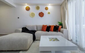 Een moderne woonkamer met een hoekbank, een witte salontafel en decoratieve wanddecoratie.
