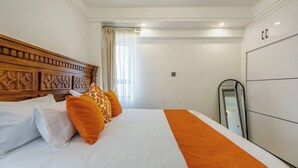 Une chambre d’hôtel avec un grand lit, une tête de lit en bois, une armoire et un miroir.