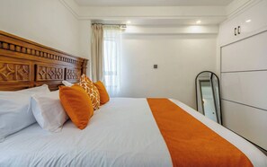 Ein Hotelzimmer mit einem großen Bett, einem Holzkopfteil, einem Kleiderschrank und einem Spiegel.