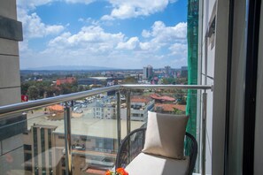 A balcony with a clear view of a cityscape, including buildings and a distant mountain range. - Cozy Nest 1BR Kilimani (Nairobi)