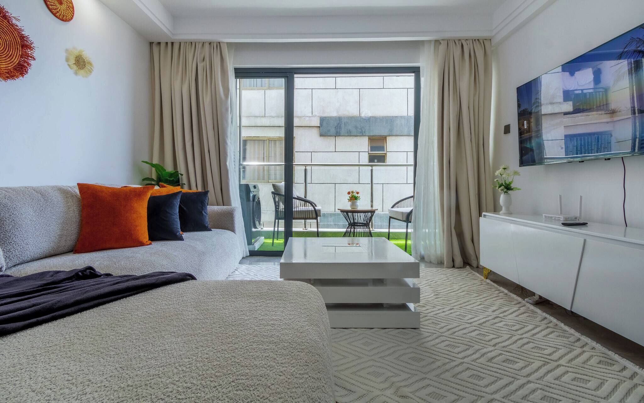 Un salon moderne avec un canapé, une table basse et un téléviseur fixé au mur.