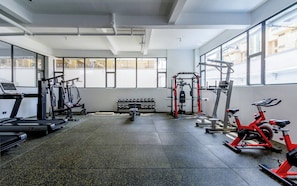 Een fitnessruimte met loopbanden, krachtapparaten en een hometrainer.