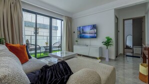 Un salon moderne avec un canapé, une table basse et un téléviseur à écran plat fixé au mur.