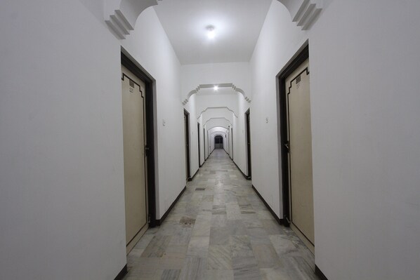 A long, narrow hallway with doors on both sides and a tiled floor.