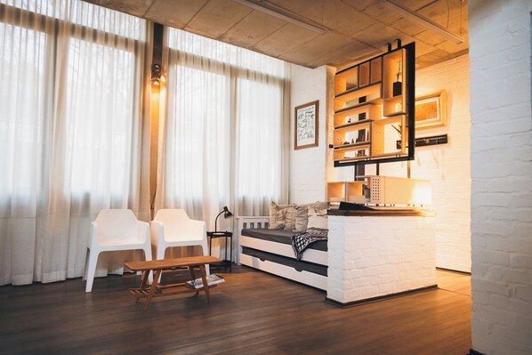 A modern living room with a white brick wall, a sofa, a coffee table, and a bookshelf.