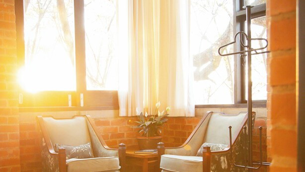 Una habitación con dos sillones, una mesita y un ventanal con cortinas.