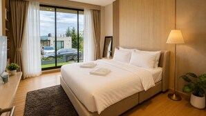 Una habitación de hotel moderna con una cama grande, un escritorio con una silla, un televisor y vistas al exterior.
