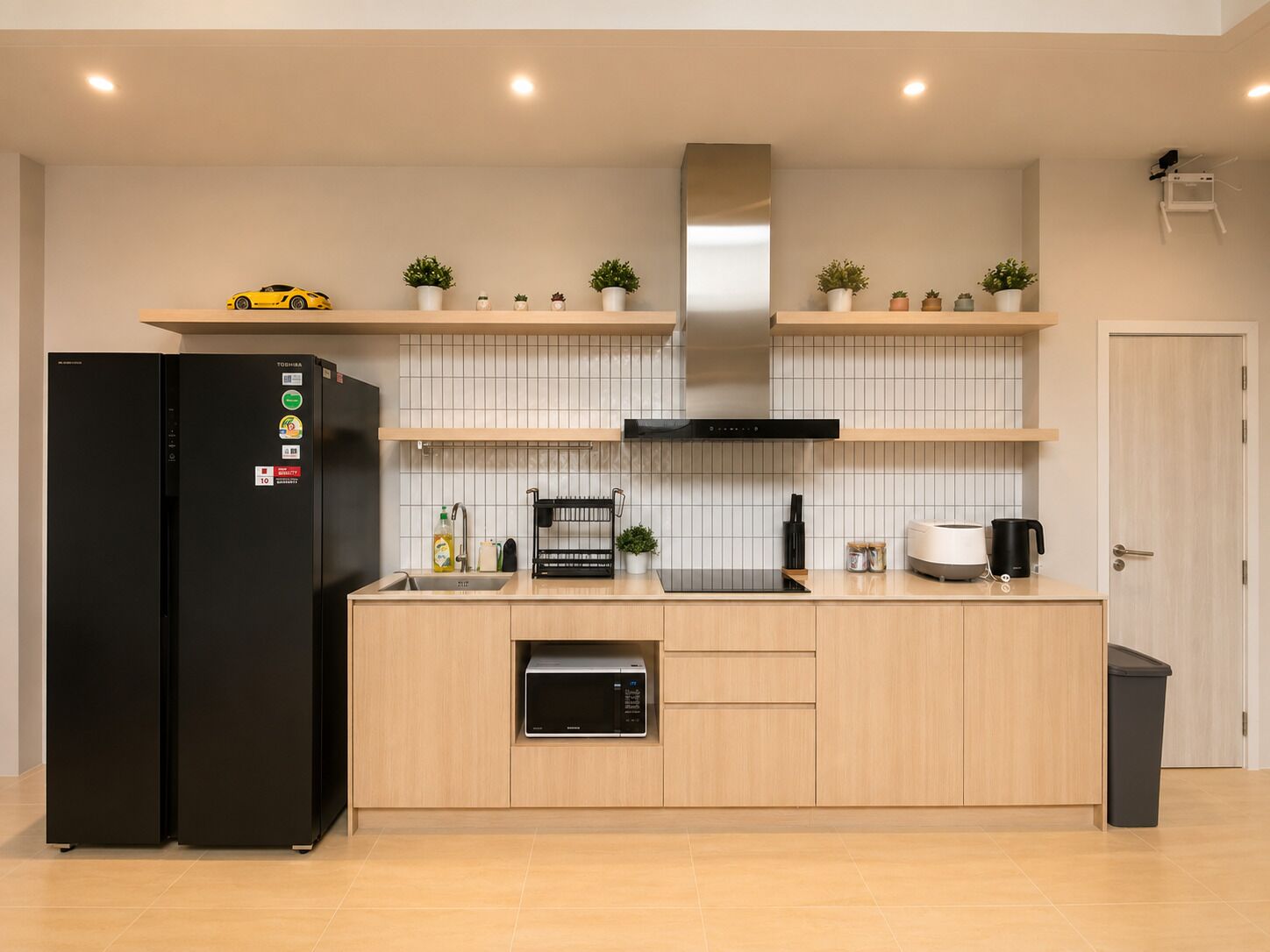 A modern kitchen with a black refrigerator, microwave, and stove, wooden cabinets, and a small island with a sink.