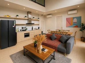 A modern living room with a sofa, coffee table, and a dining area with a table and chairs.