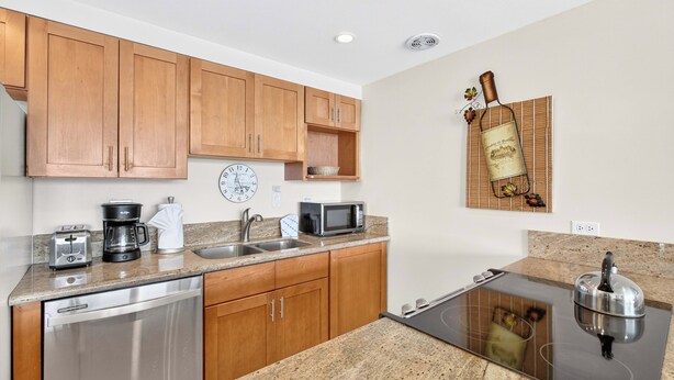 A modern kitchen with wooden cabinets, a dishwasher, a coffee maker, a microwave, and a kettle. - New Listing Oceanview Guaranteed (Lahaina)