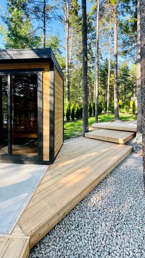 A modern wooden cabin with a deck, surrounded by a forest. - The Lake Villa
Cedar Sauna, Hot Tub, and Private Putting Green 
Escape for Two (Ingramport)