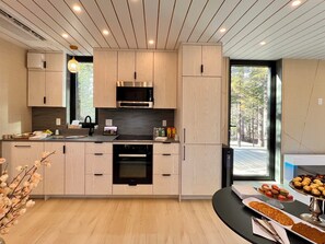 A modern kitchen with wooden cabinets, a built-in oven, and a dining area with a table set for a meal. - The Lake Villa
Cedar Sauna, Hot Tub, and Private Putting Green 
Escape for Two (Ingramport)