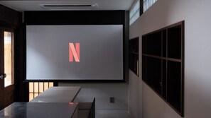 A modern interior with a large projection screen displaying a letter 'N', a minimalist table, and a window with blinds. - Private Luxury Hanok I Jacuzzi I Jongro I Gwanghwamun I SUB3min (Seoul)