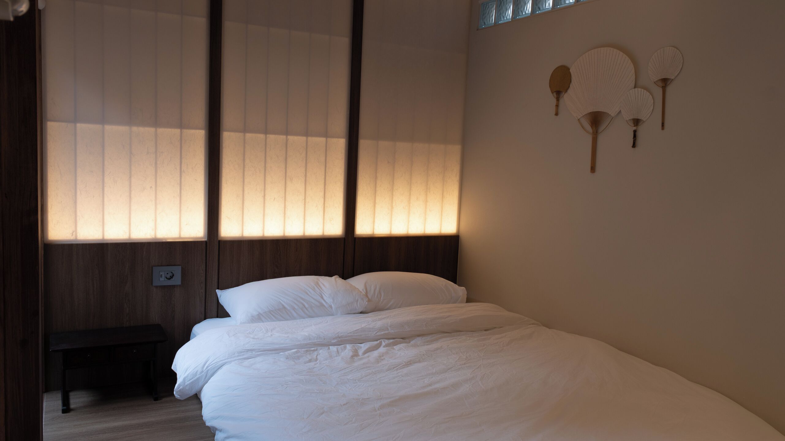 A bedroom with a bed, a nightstand, and a wall-mounted fan.