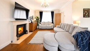 A living room with a fireplace, a sofa, a television, and a chandelier. - Milcourt -  a managed house that sleeps 8 guests  in 4 bedrooms (Canterbury)