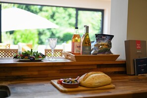 Ein Holztisch mit Salat, einem Glas, Weinflaschen, einem Brötchen und einem Buch.