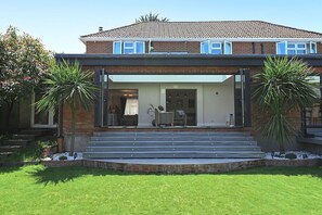 A two-story house with a covered front porch, a brick exterior, and a well-maintained lawn. - Milcourt -  a managed house that sleeps 8 guests  in 4 bedrooms (Canterbury)