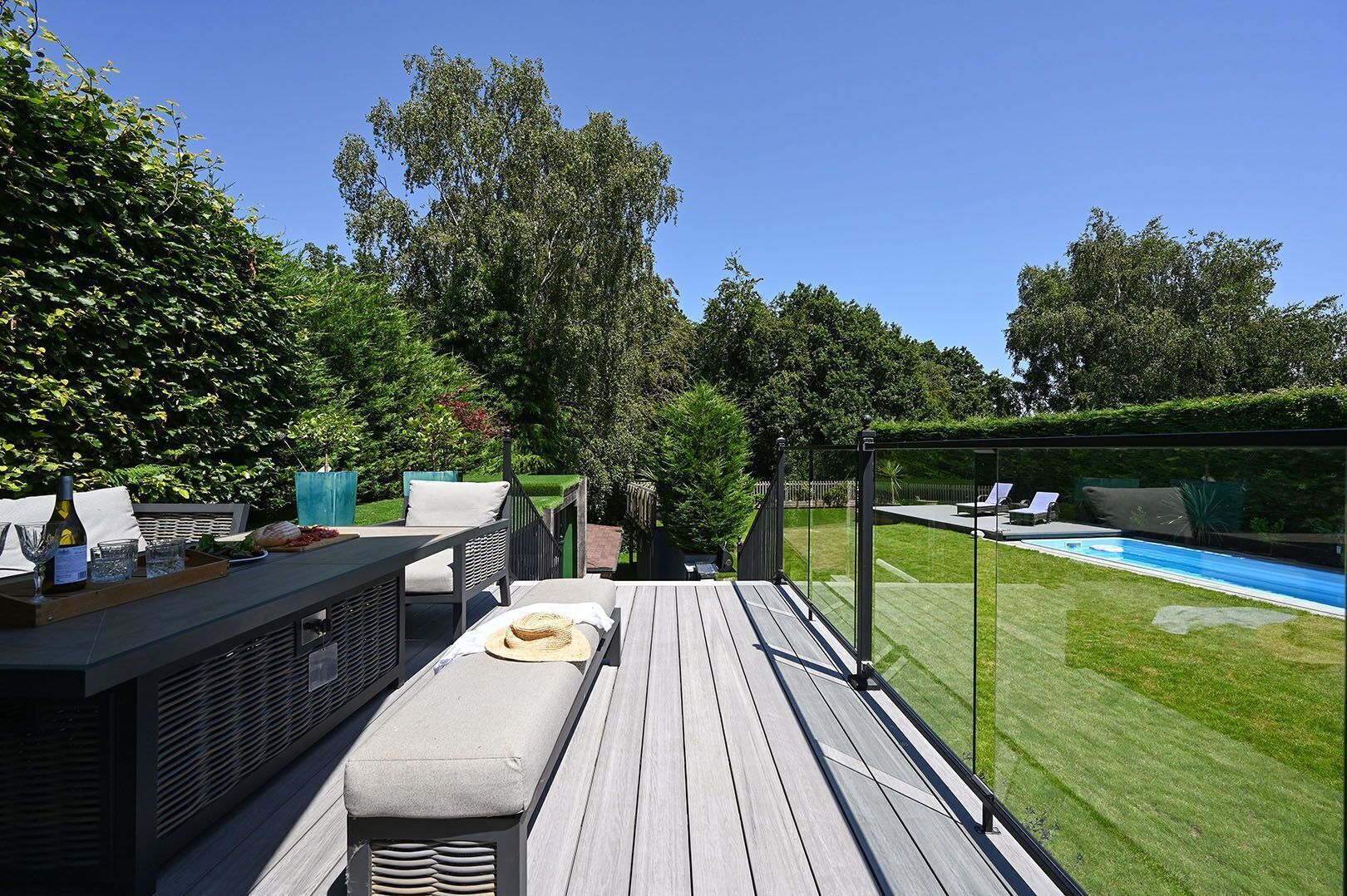 An outdoor deck with a pool, lounge chairs, and a dining area with a table and chairs.