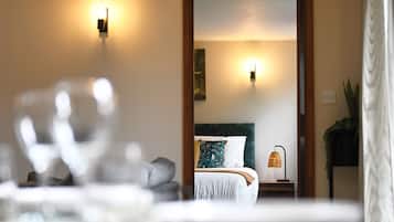 A bedroom with a bed, bedside lamps, and a view into another room.
