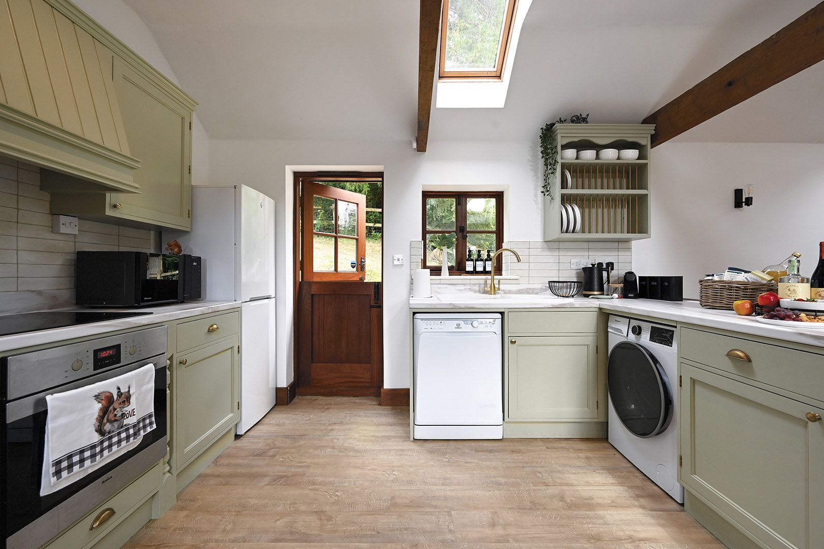 A kitchen with a dishwasher, oven, microwave, and a window above the sink.
