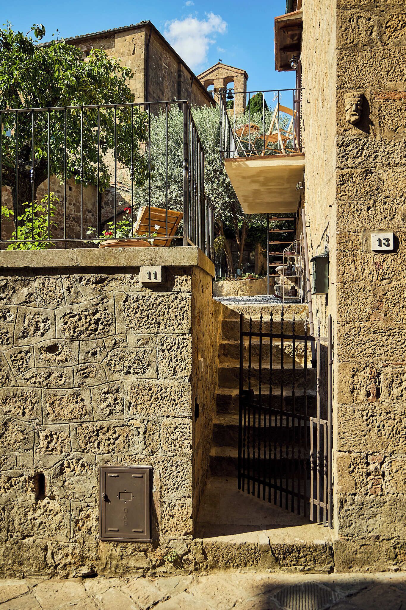 A stone building with a metal gate and a staircase leading to a balcony.