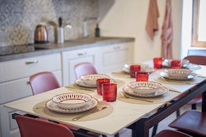 A dining table set with plates, glasses, and cutlery in a kitchen with a tiled backsplash and cabinets. - A romantic house with a garden in Val d'Orcia. Between the past and the present. (Monticchiello)