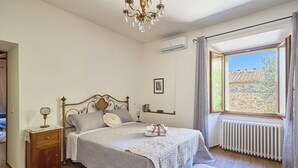 Ein Schlafzimmer mit Bett, Nachttisch, Lampe, Heizkörper und einem Fenster mit Blick.