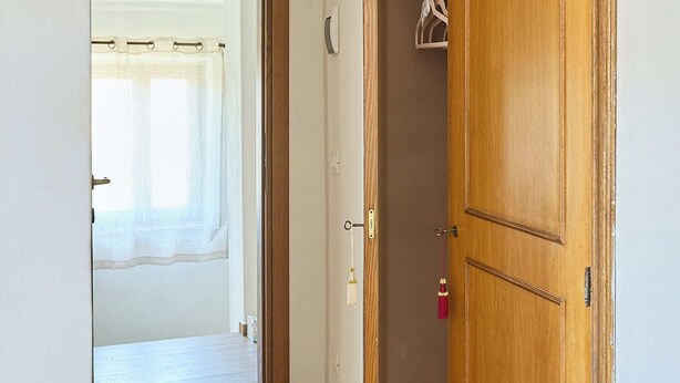 Ein Flur mit einem Holzschrank, einer Tür zu einem anderen Raum und einem Fenster mit Vorhängen.