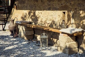 A rustic outdoor seating area with a wooden bench, stone blocks, a lantern, and a vase. - A romantic house with a garden in Val d'Orcia. Between the past and the present. (Monticchiello)