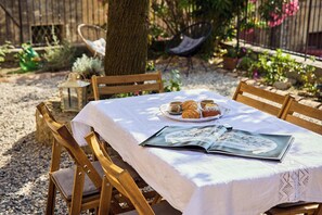 A table with a white tablecloth, a plate of pastries, a cup, and an open magazine. - A romantic house with a garden in Val d'Orcia. Between the past and the present. (Monticchiello)
