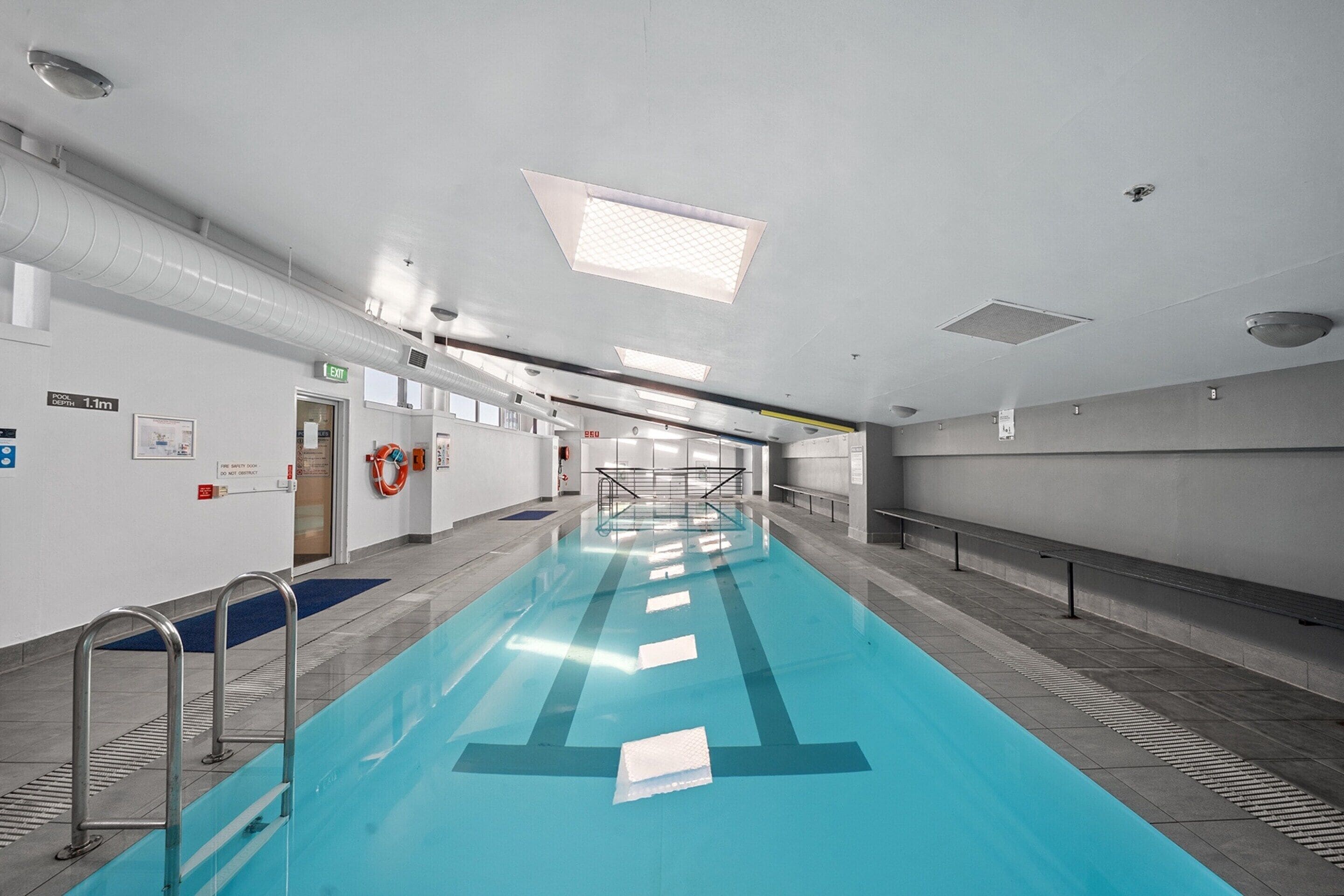 Una piscina con carriles delimitados, señales de seguridad y un flotador en la pared.