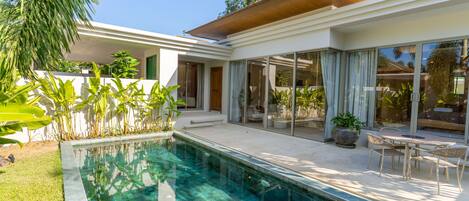 Una casa moderna con piscina, ventanas amplias y un patio.
